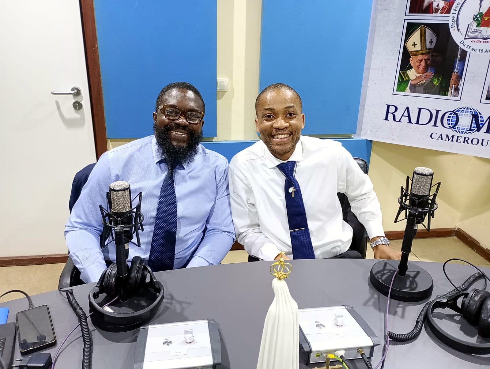 Two guests smiling at the Radio Maria Cameroon studio microphones